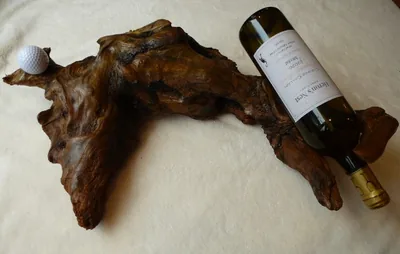 Driftwood wine cradle holding a Heron's Nest wine bottle and a golf ball